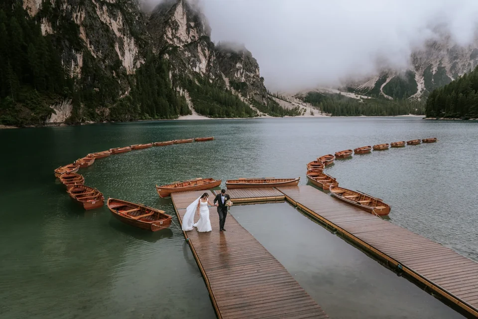 The couple on the Braies boathouse jetty beside the row of wooden boats
