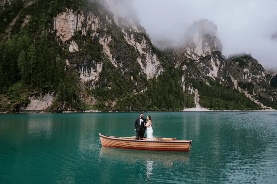 The couple in a wooden boat on the turquoise water of Lago di Braies