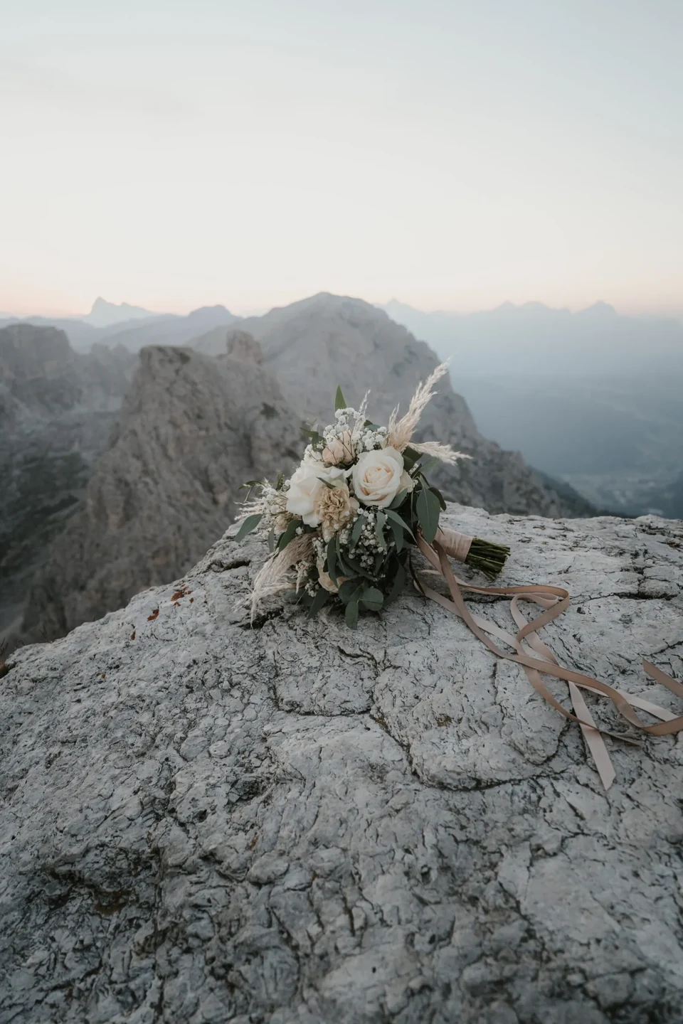 A bouquet resting on summit rock with misty peaks beyond