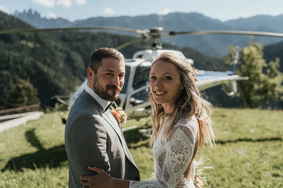 The couple embracing in a summer meadow, the helicopter behind them