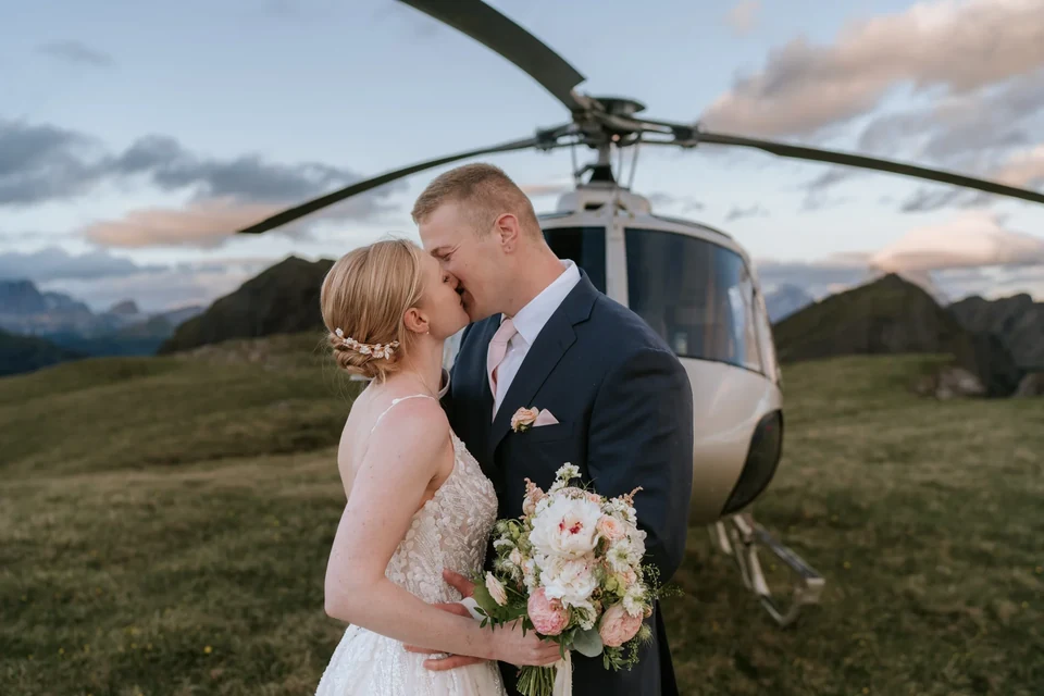The couple kissing in front of the helicopter in warm light