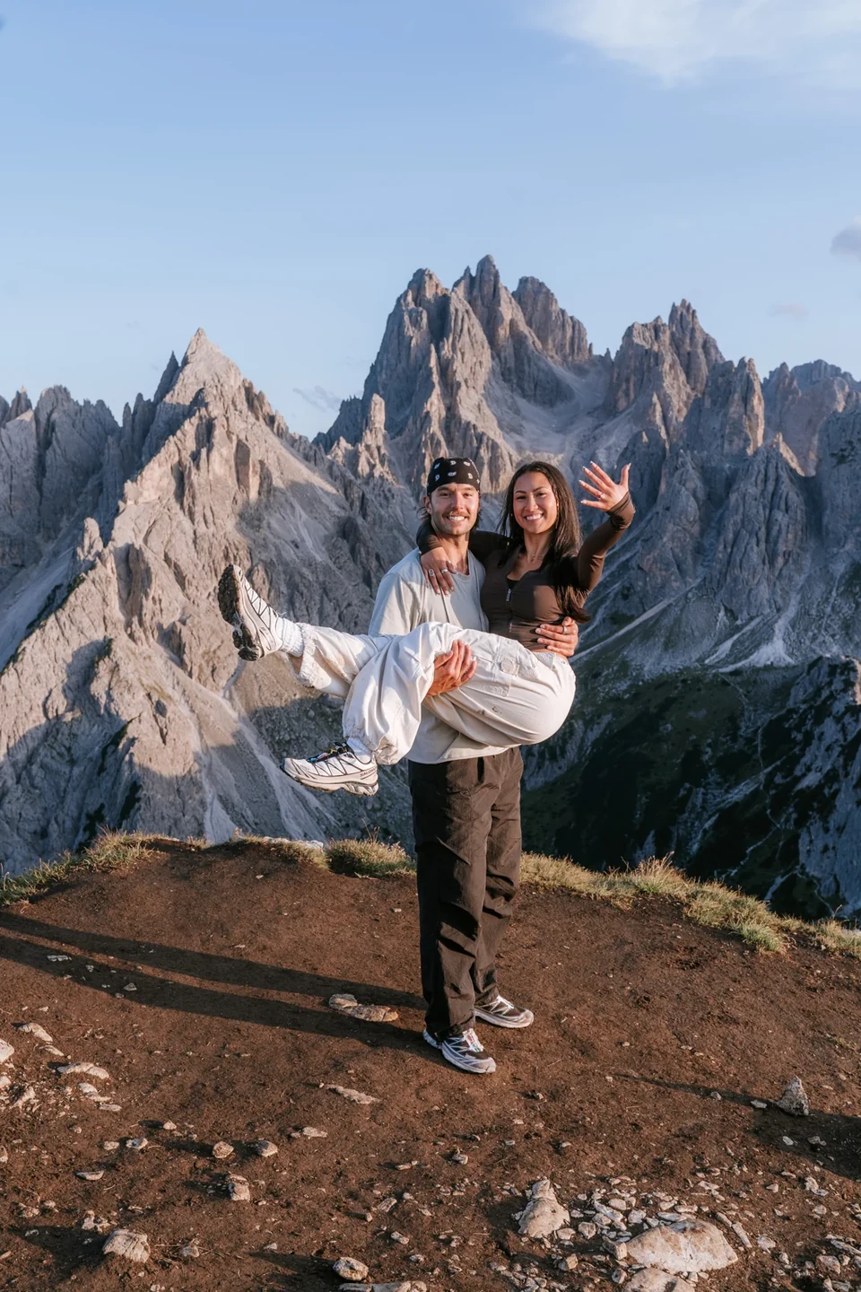 He lifts her in joy, the Cadini spires behind
