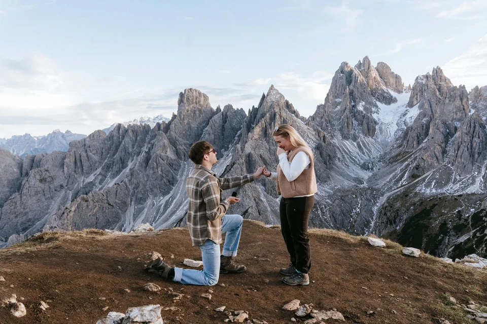 Kneeling to propose beneath jagged Dolomite spires, shot from a distance