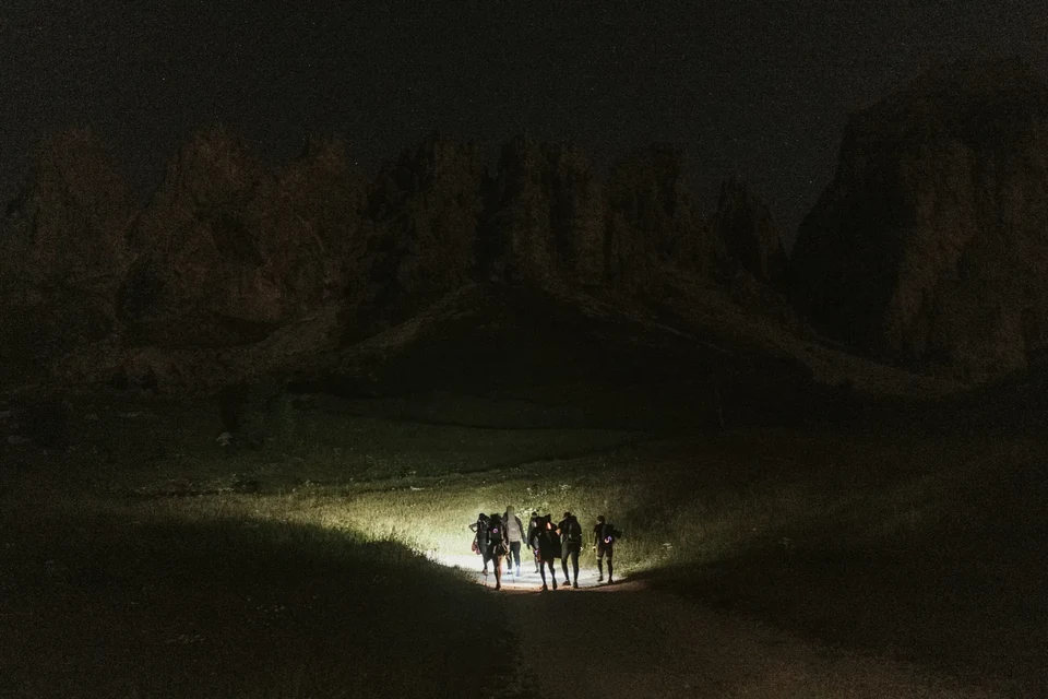 Die Gruppe nur vom Strahl einer Stirnlampe erhellt auf dem dunklen Weg