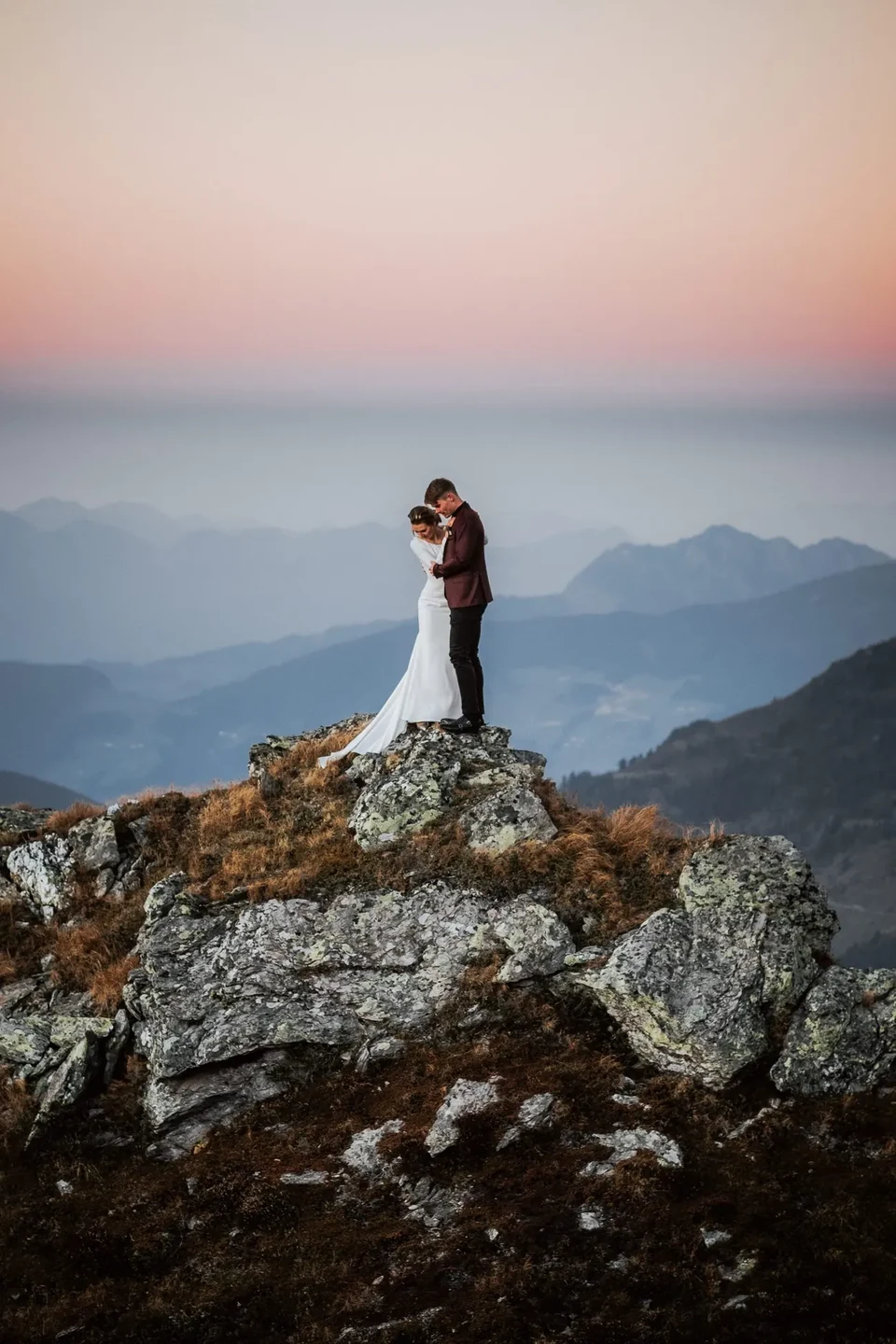 Das Paar auf einer Felskanzel vor den Bergen im Sonnenuntergang