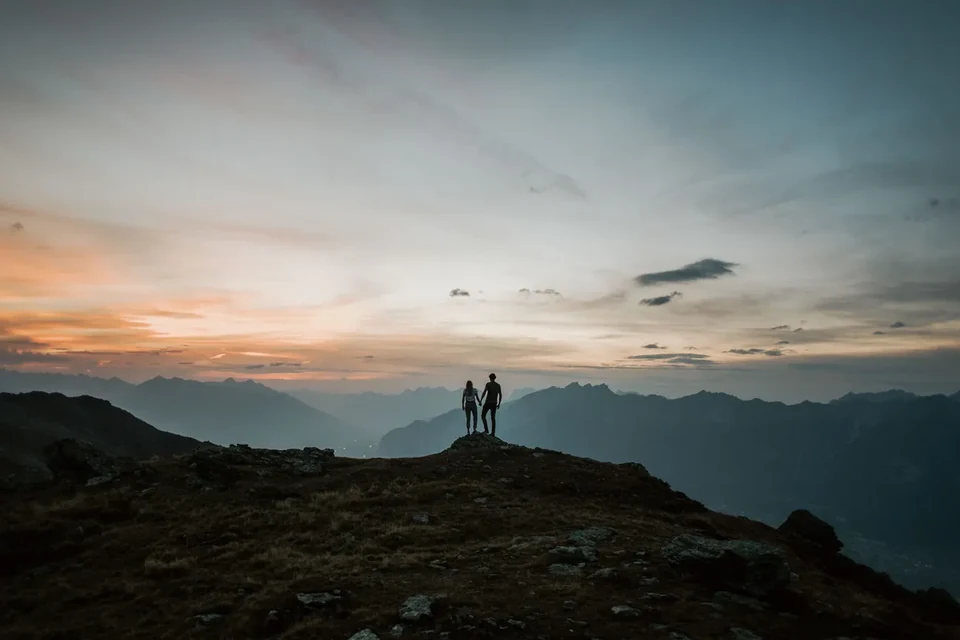 Das Paar als Silhouette auf dem Grat unter weitem Abendhimmel