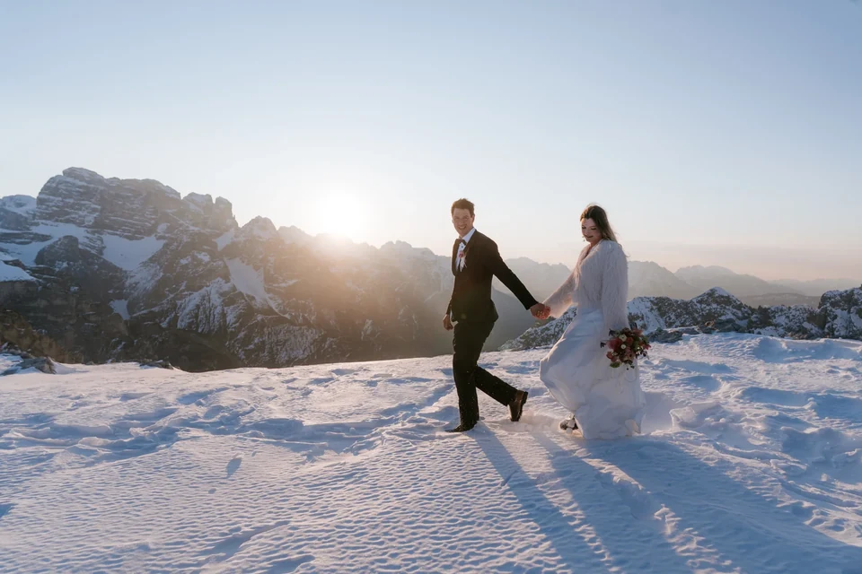 Das Paar geht durch den Schnee, die tiefe Sonne im Rücken